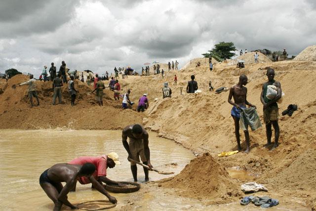 In a desert, men forage for metals in a pool of water.