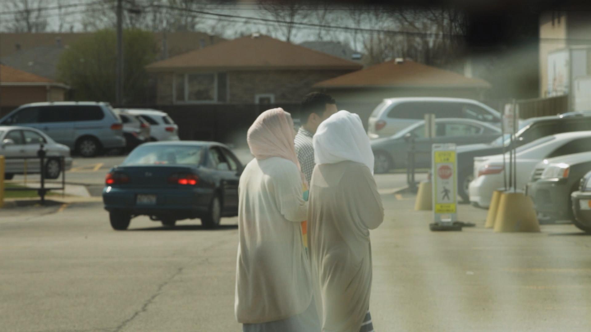 A pair of young girls in hijab walk outside of school.