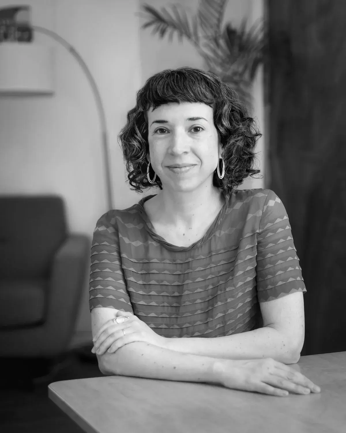 A white woman with dark wavy hair in hoop earrings.