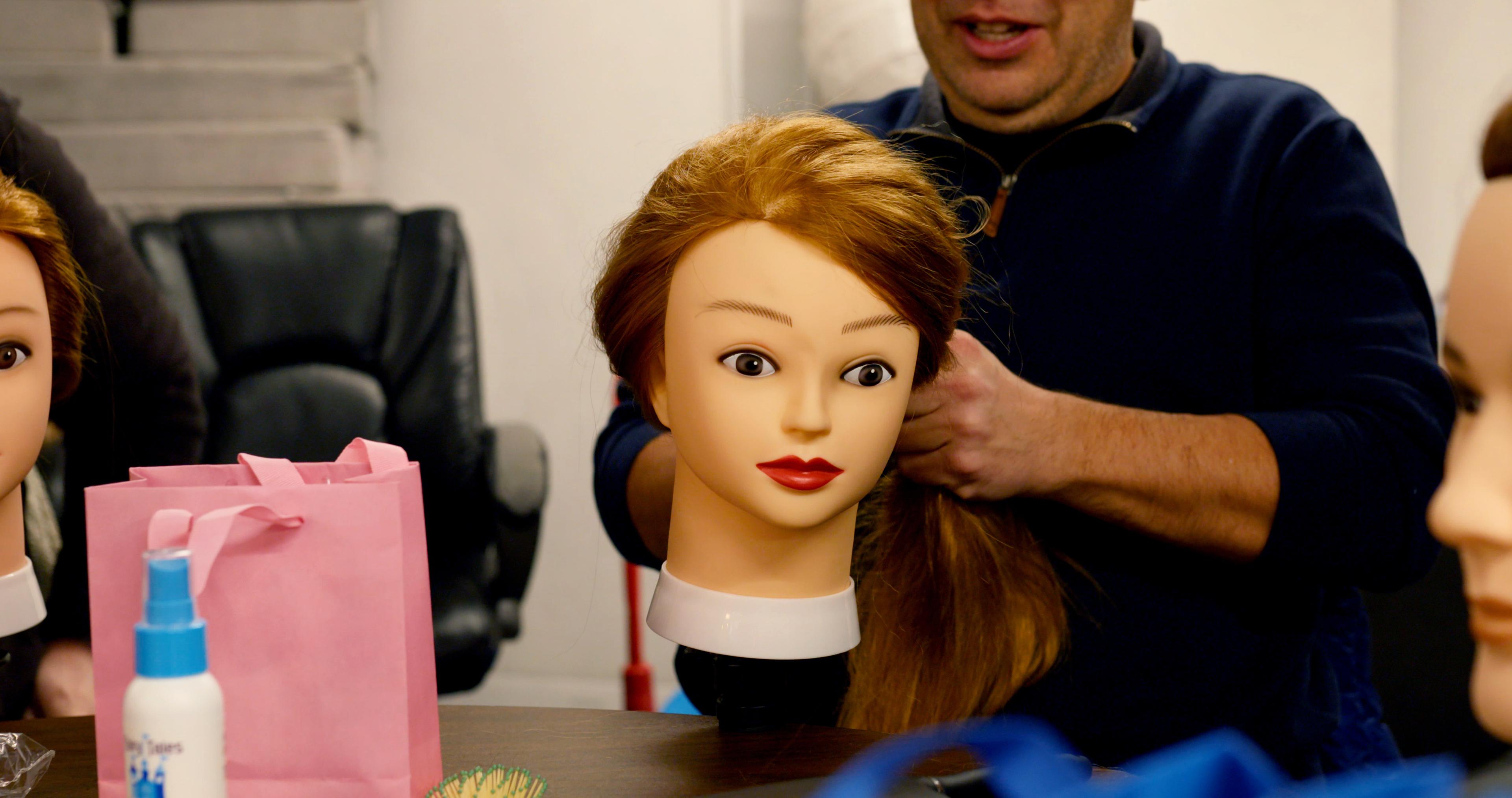 A person is doing a mannequin's hair.