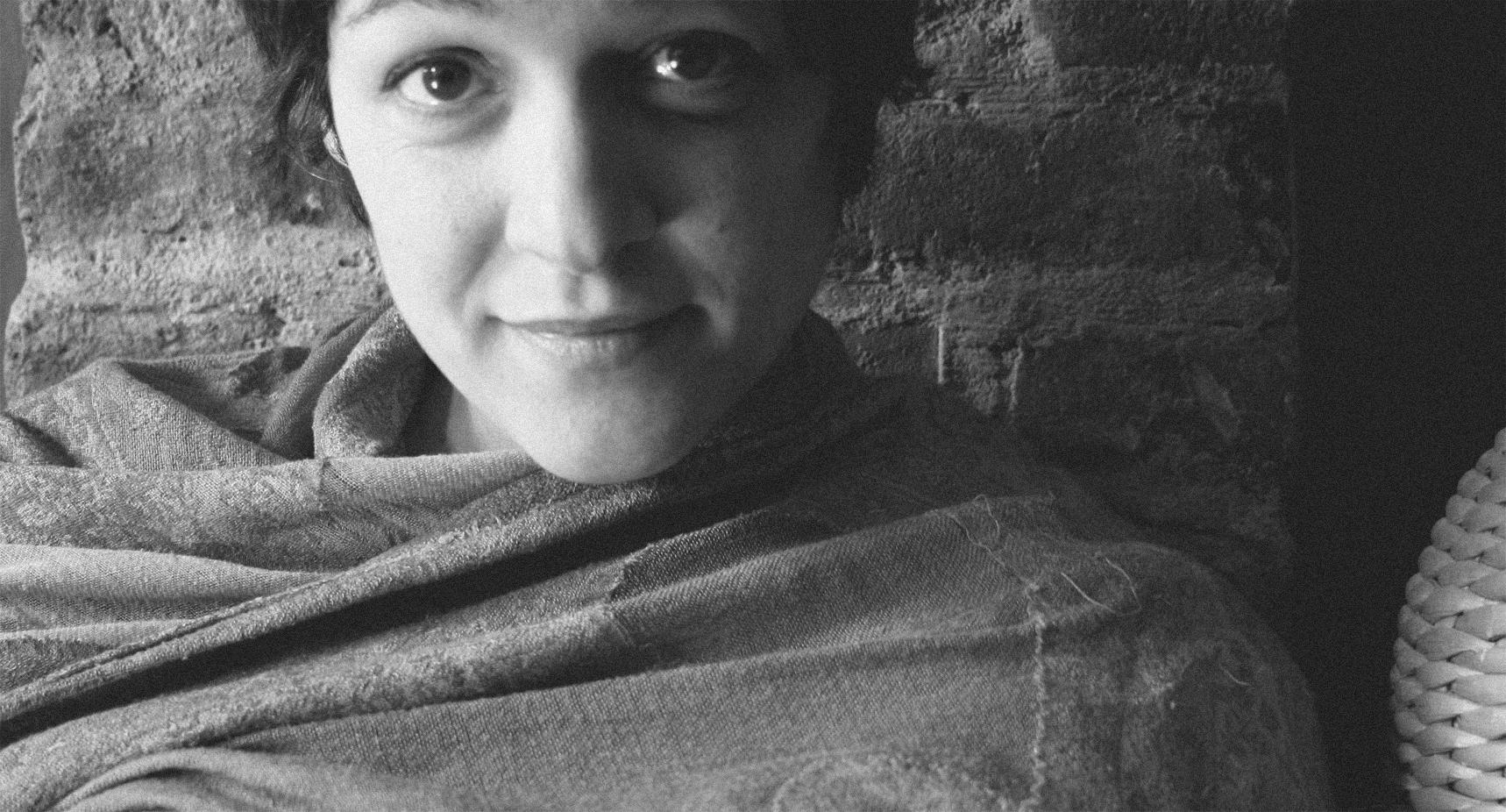 A black and white portrait of a woman smiling and looking into the camera.