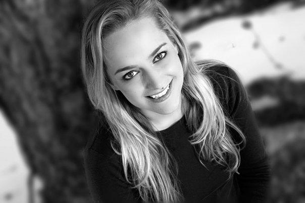 A black and white portrait of a woman looking into the camera and smiling.