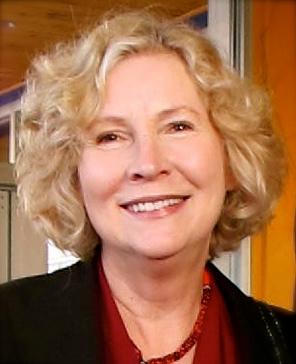 A photo of a woman in a doorway smiling at the camera.