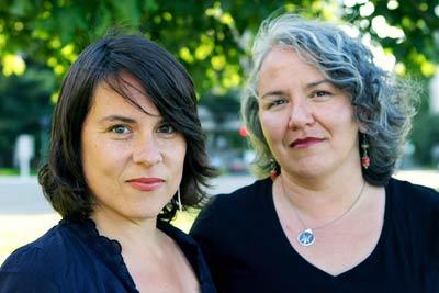 Two women stand next to each other and smile into the camera.