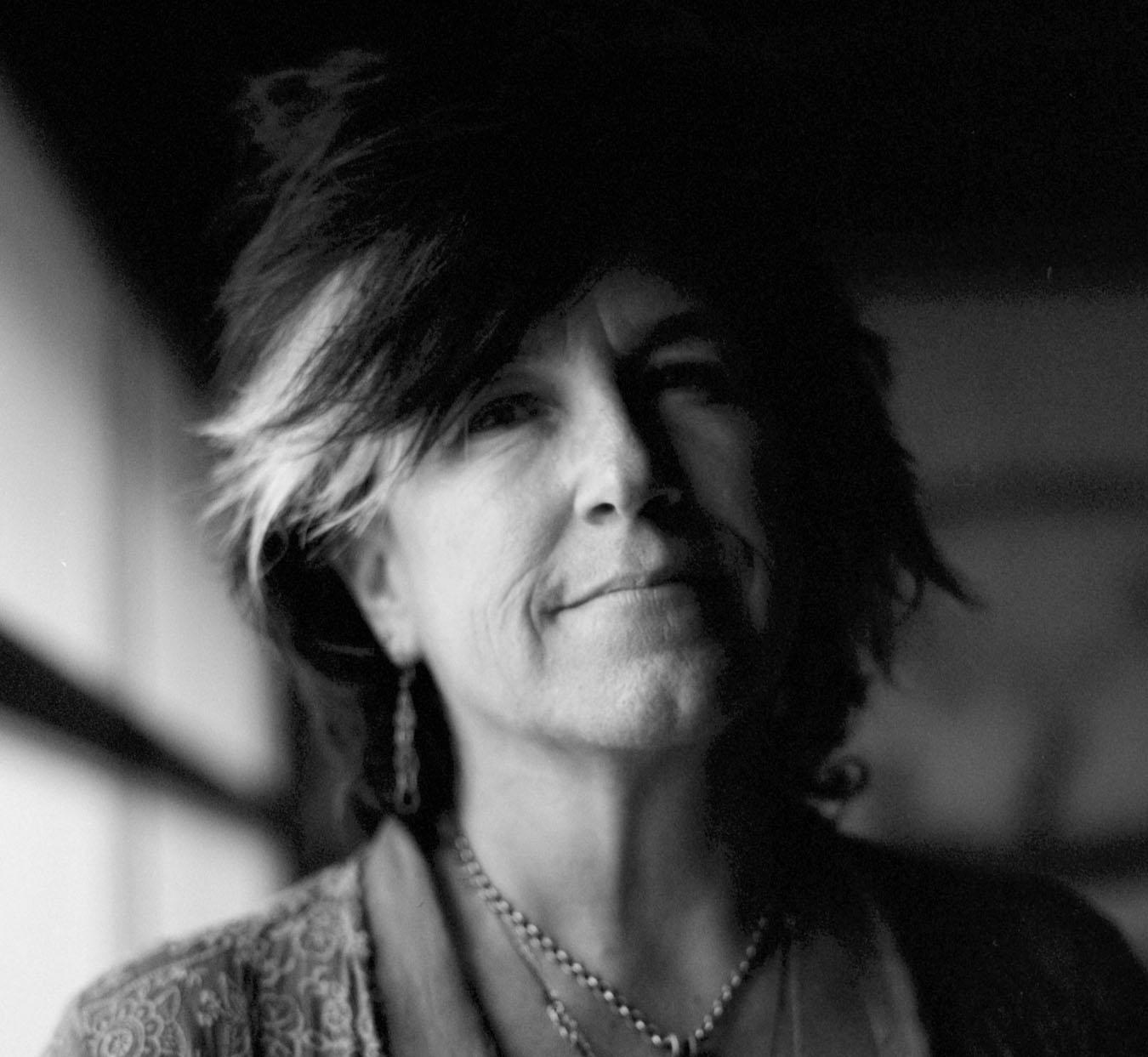 A black and white portrait of a woman smiling into the camera.