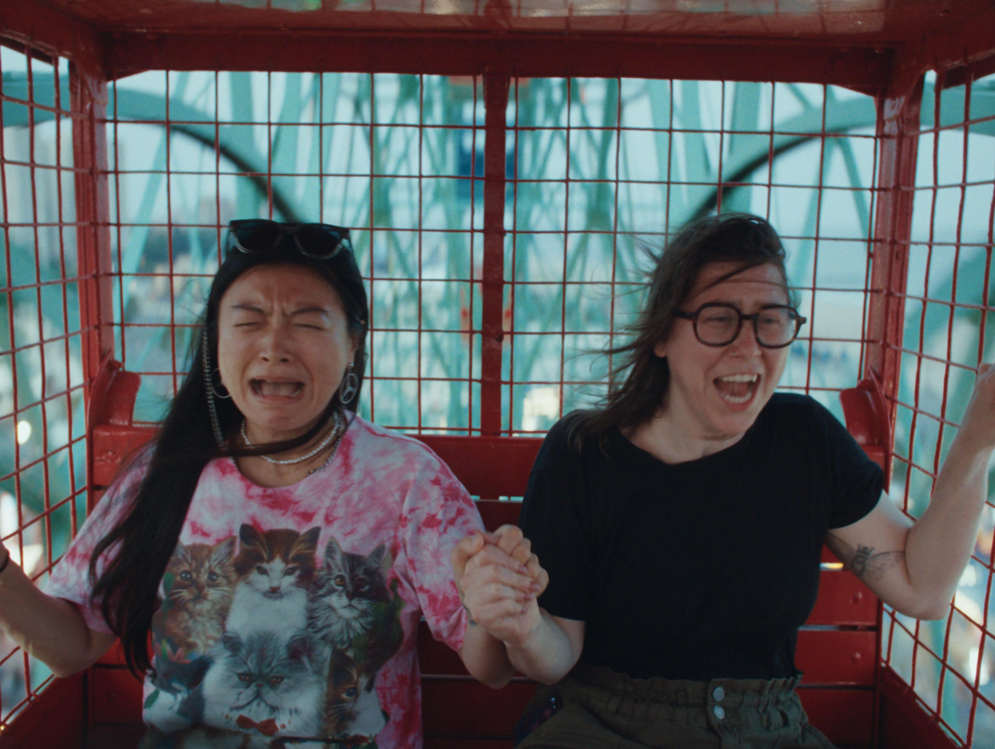 Two people hold hands while looking scared and surprised.