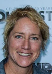 A photo of a woman on a red carpet smiling at the camera.