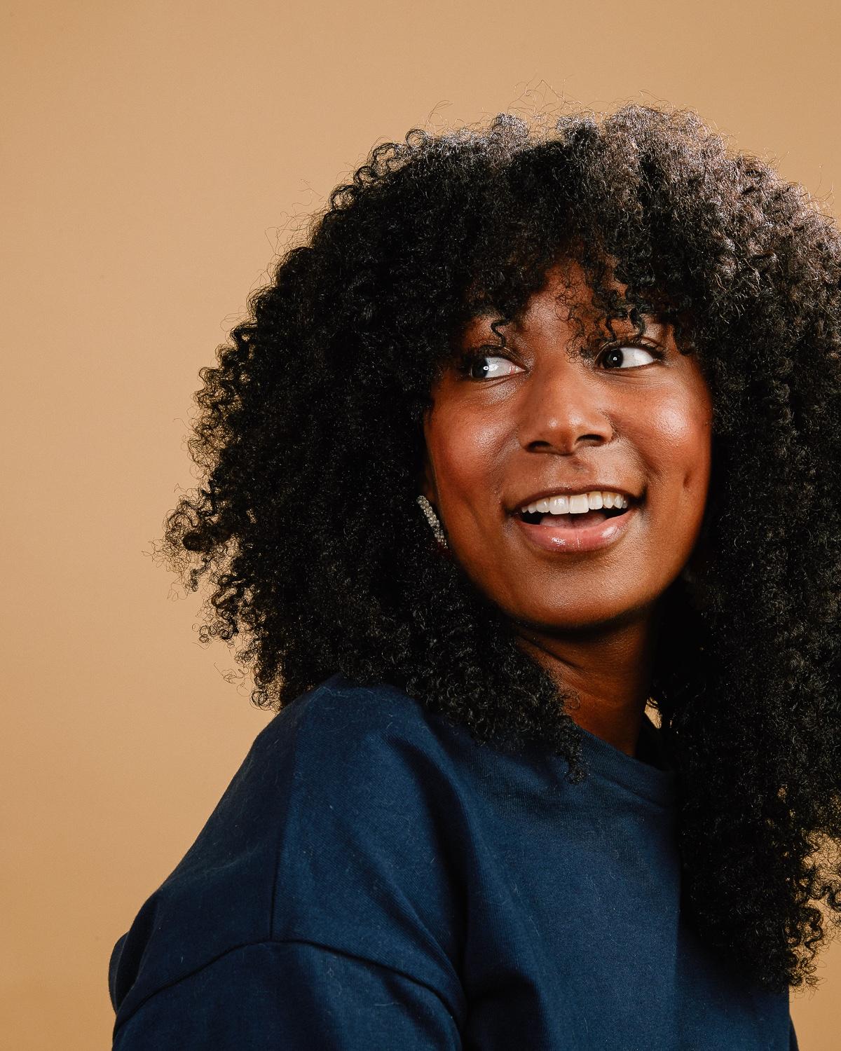Chelsi Bullard looking to the side and smiling. She has very curly, shoulder-length hair.