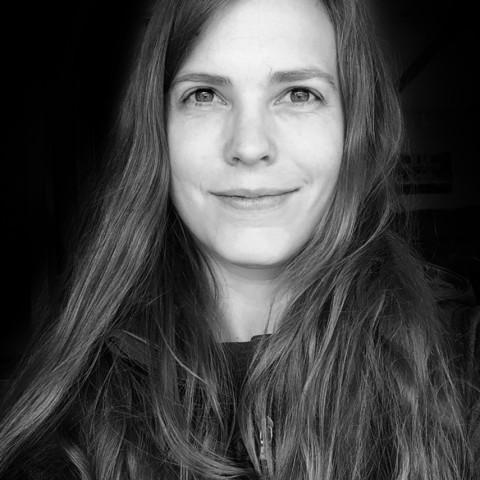 Headshot of a woman with long hair and smiling at the camera