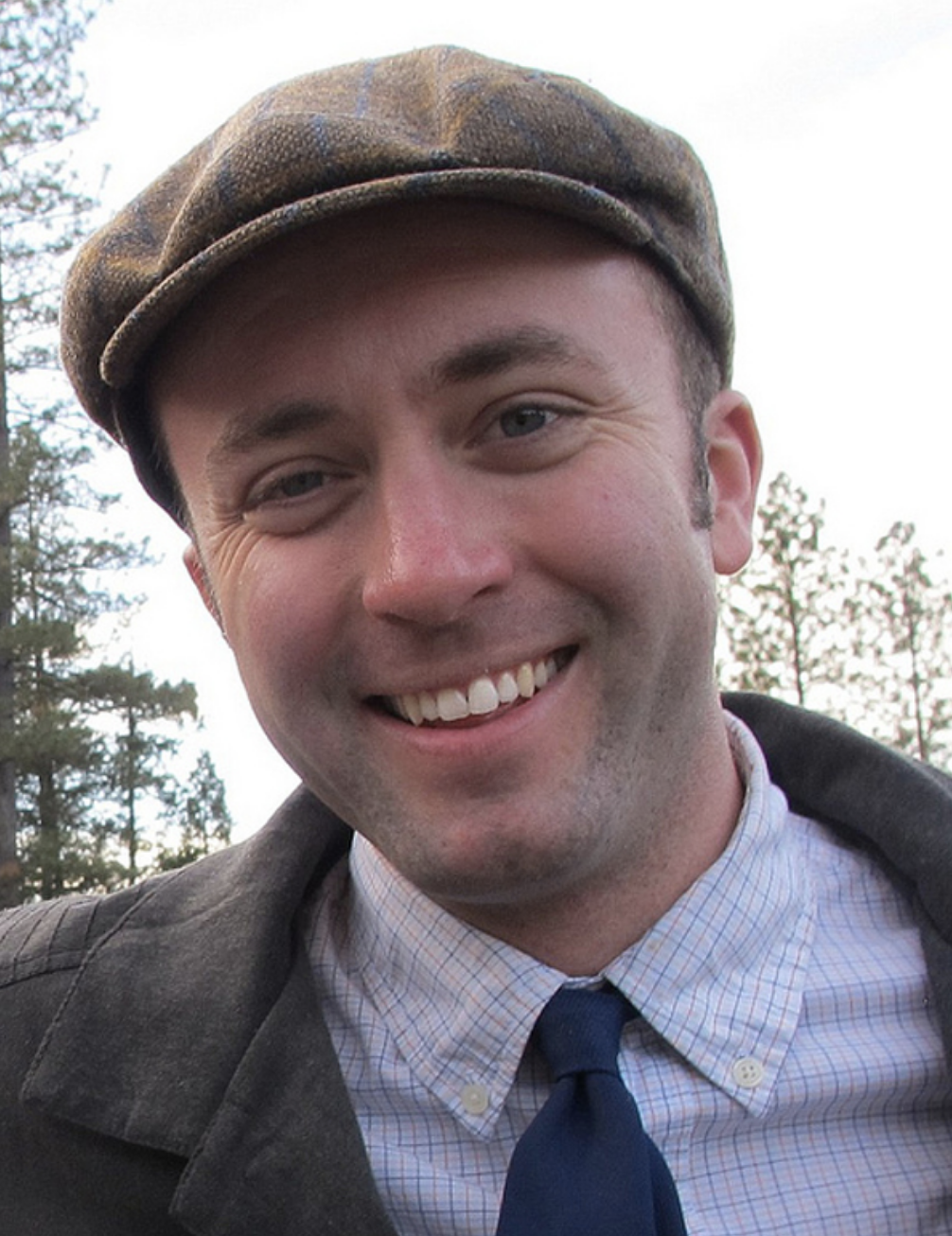 Headshot of Ian Cheney from the shoulders up wearing a hat.