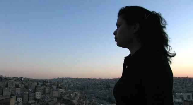The silhouette of a woman standing against the sunset overlooking Baghdad.