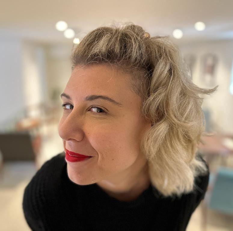 Andrijana Sofranić Šućuris, a blonde woman with dark red lipstick, looks directly at the camera and smiles.