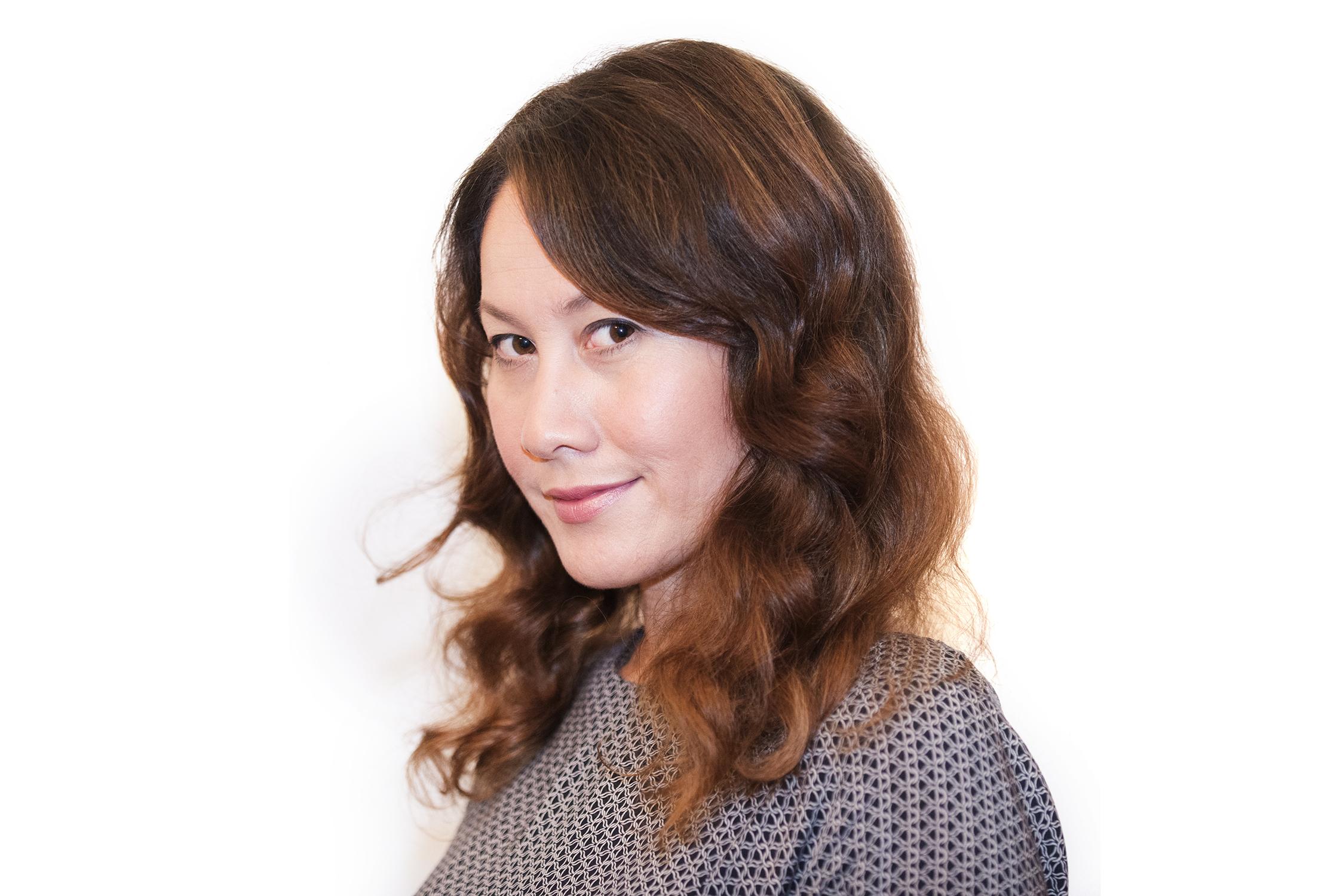 A portrait of a woman with a playful expression looking into the camera.