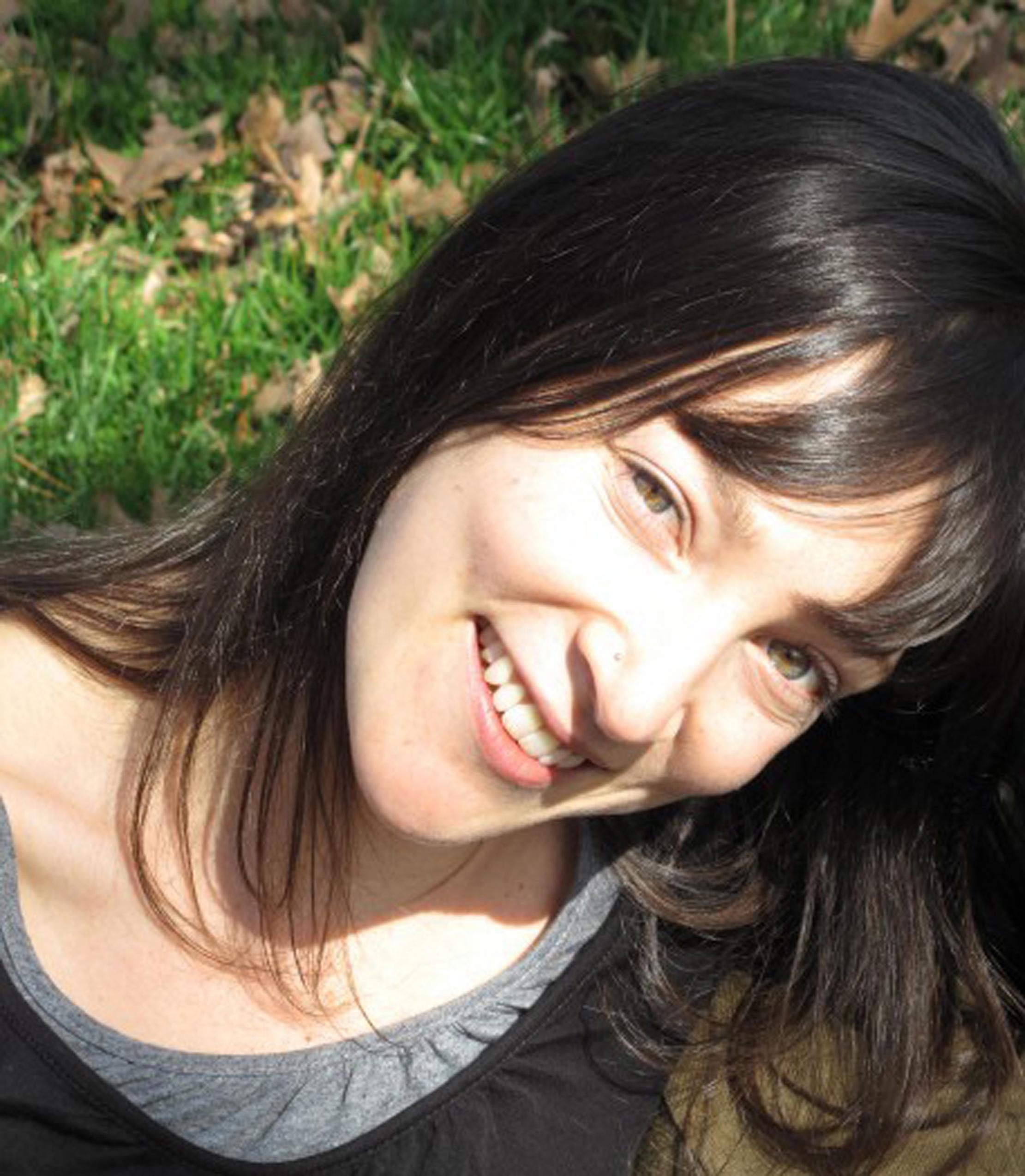 A woman smiles and tilts her head.