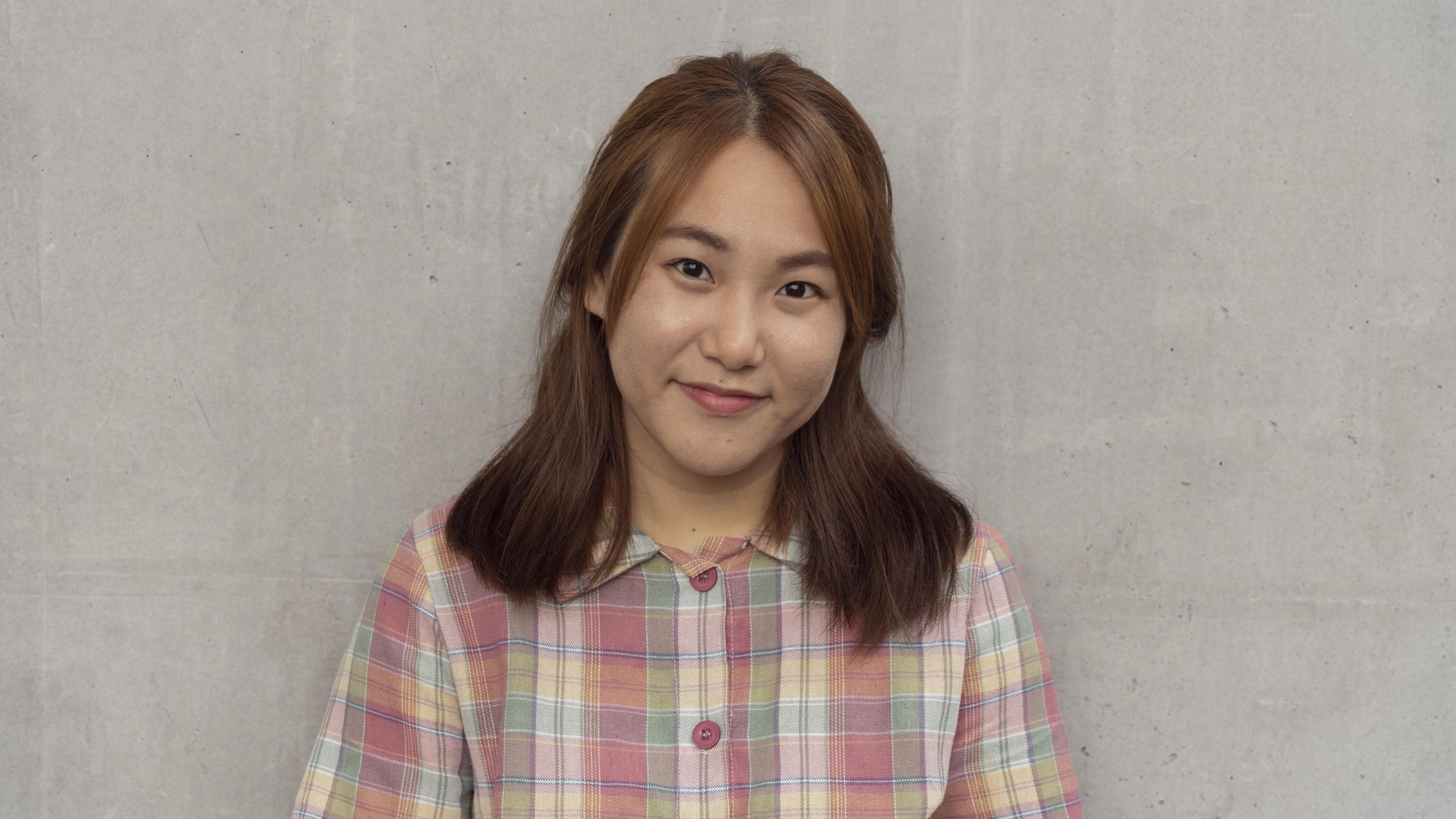 Headshot of woman with light brown hair wearing a button up flannel smiling at the camera.