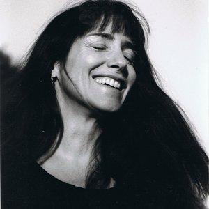 A black and white headshot of a woman smiling with her eyes closed.