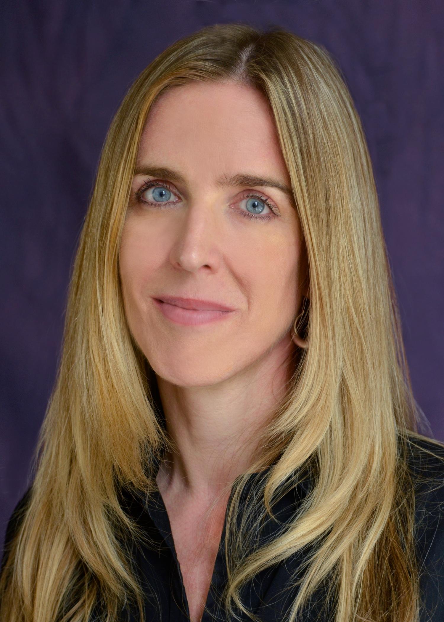 María Teresa Rodríguez looks into the camera. She has long blonde hair and is wearing a black shirt.