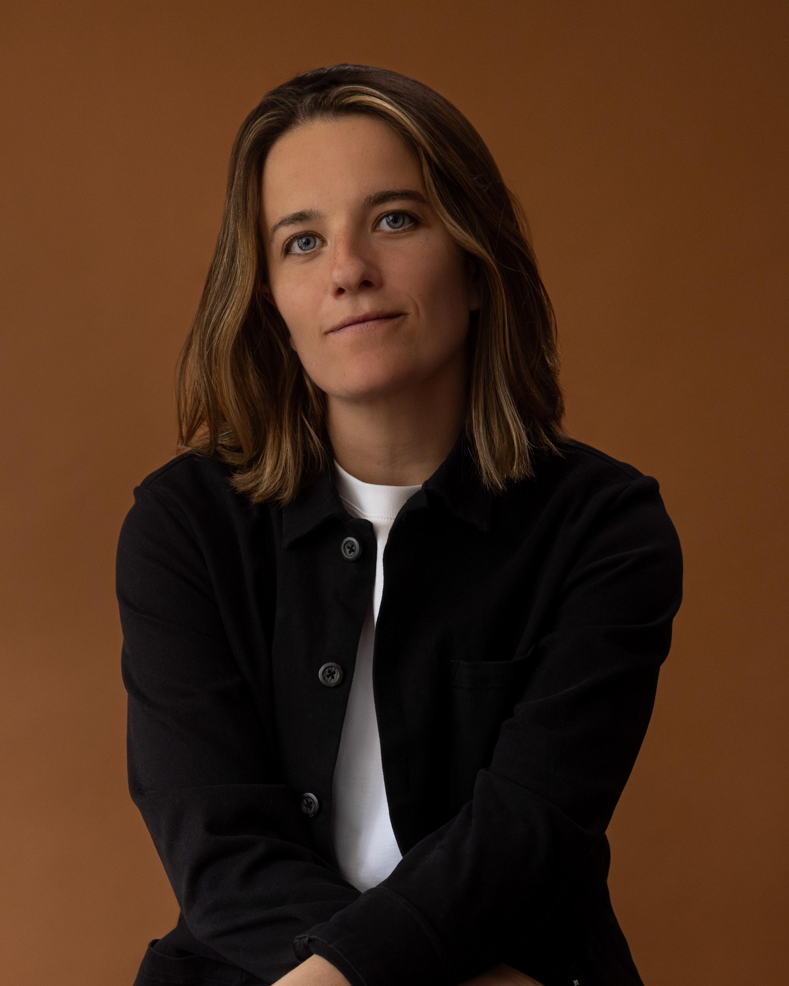 Queer woman looks directly at the camera in a headshot