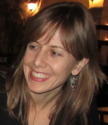 Margo Guernsey looks away from the camera smiling. SHe has bangs and blonde hair.