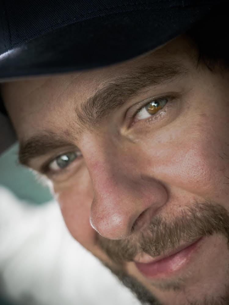 A zoomed in headshot of Anton Wenzel where you see his eyes, nose, and mouth. Anton is half smiling at the camera.